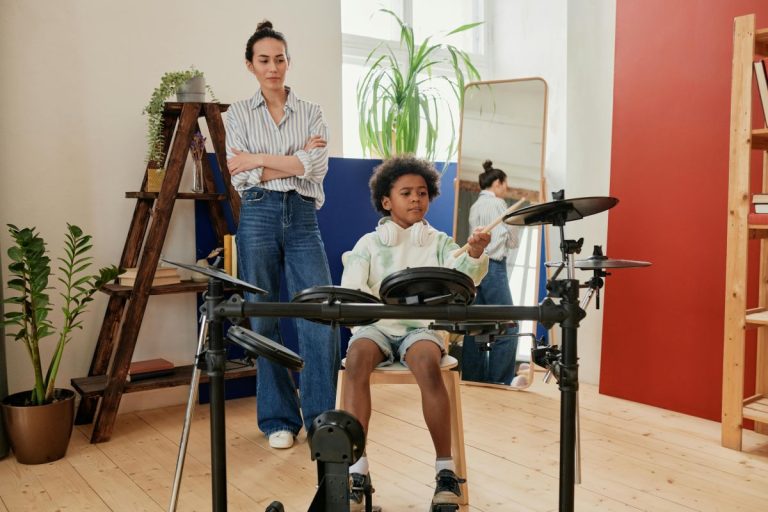 A woman teaching a boy to play drums in a cozy room.