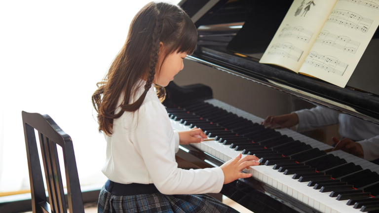 Young girl playing the piano while looking at sheet music