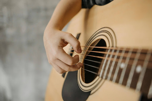 Close-up of a person's hand strumming an acoustic guitar