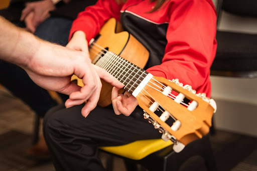 Instructor guiding student's hand on a classical guitar
