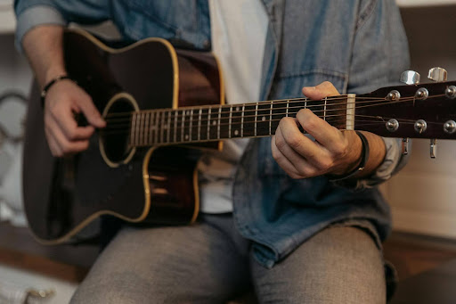 A person playing chords on acoustic guitar