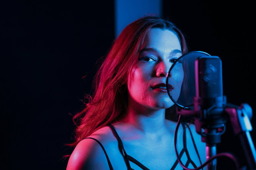 A woman singing into a professional studio microphone