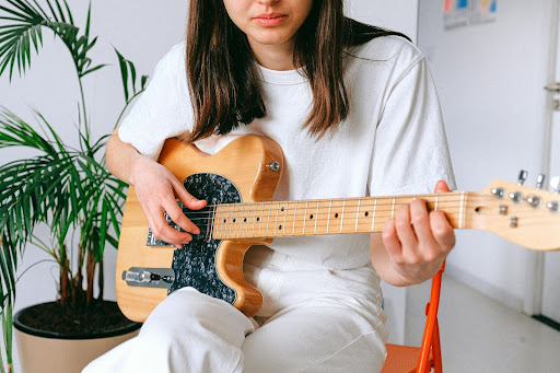 Woman playing a natural wood electric guitar