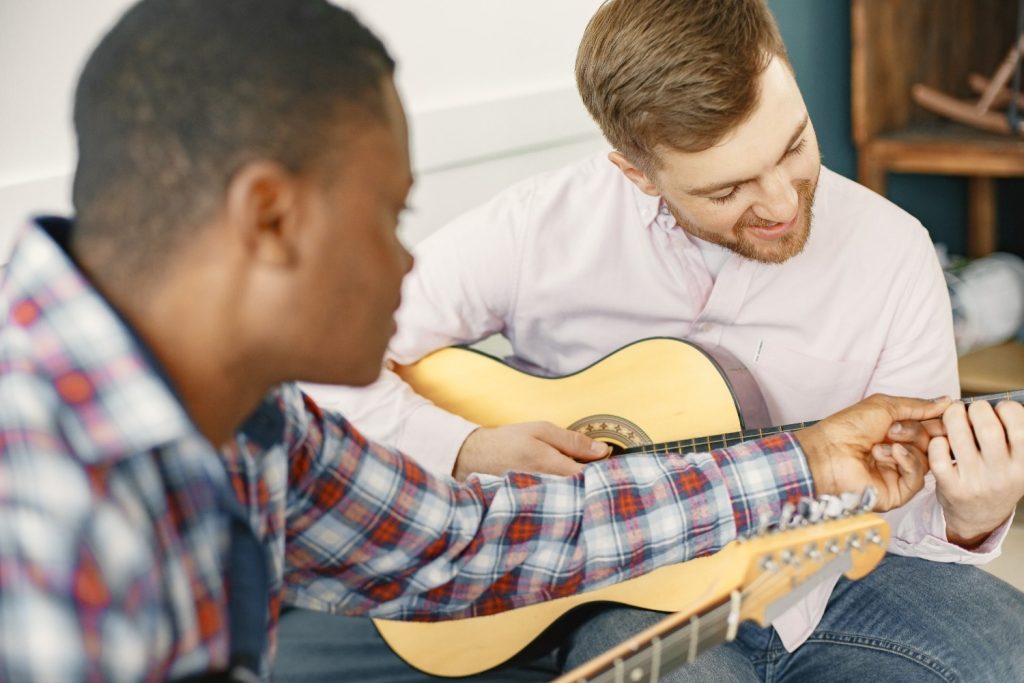 A man learns chord placement during a guitar lesson