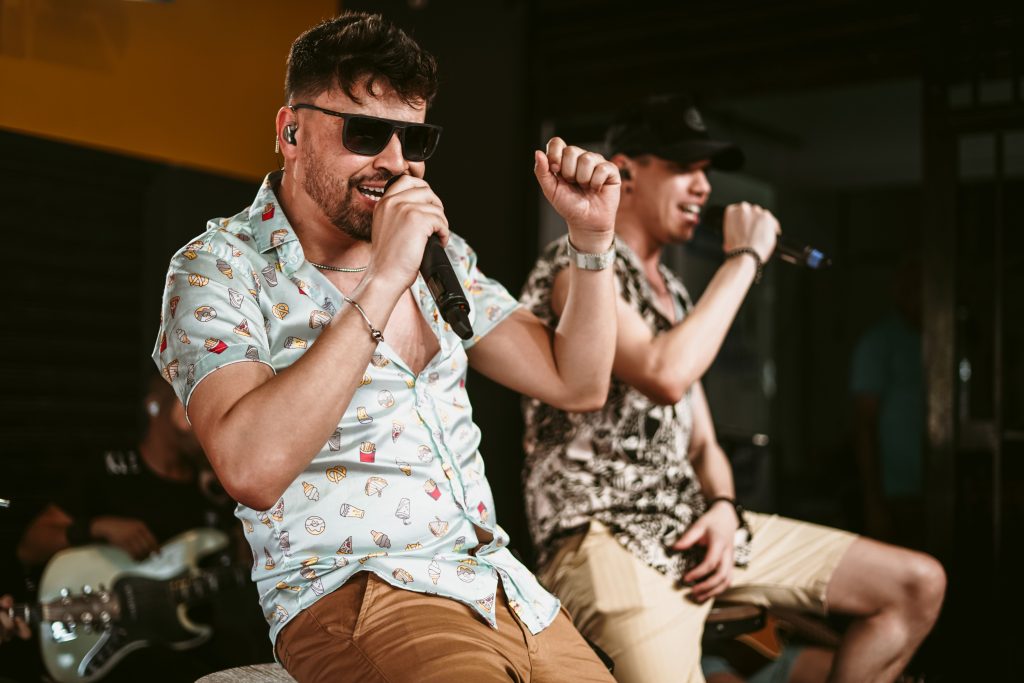 Two men singing into microphones during a live music performance