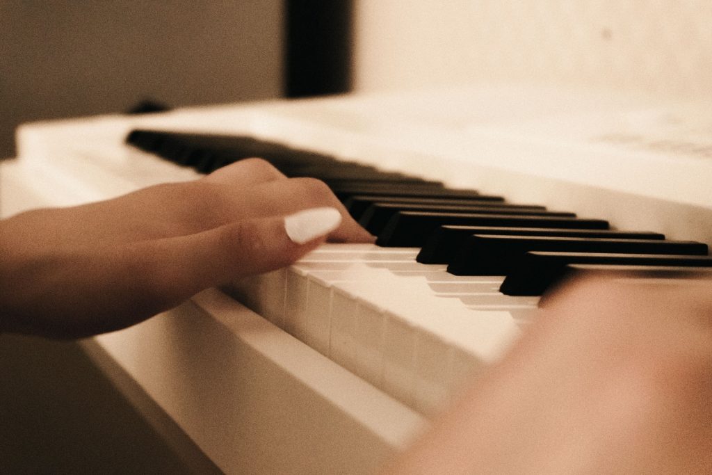 A hand playing the keys on a white piano