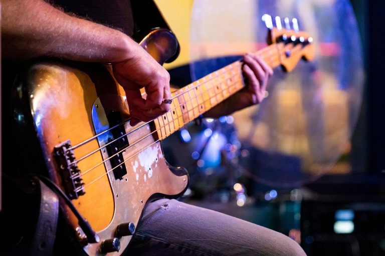 A musician's hands playing an electric bass guitar