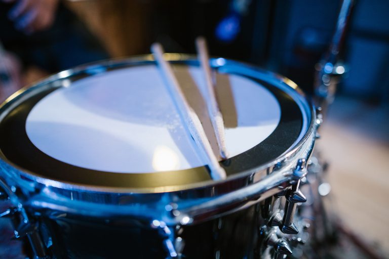 A pair of wooden drumsticks resting on a snare drum